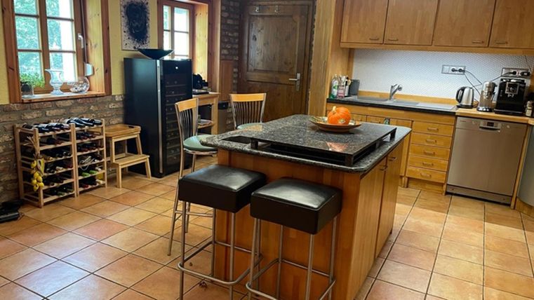 Een moderne keuken met een centrale eiland en barstoelen. Ze is licht en goed uitgerust, met hout- en steenlook.