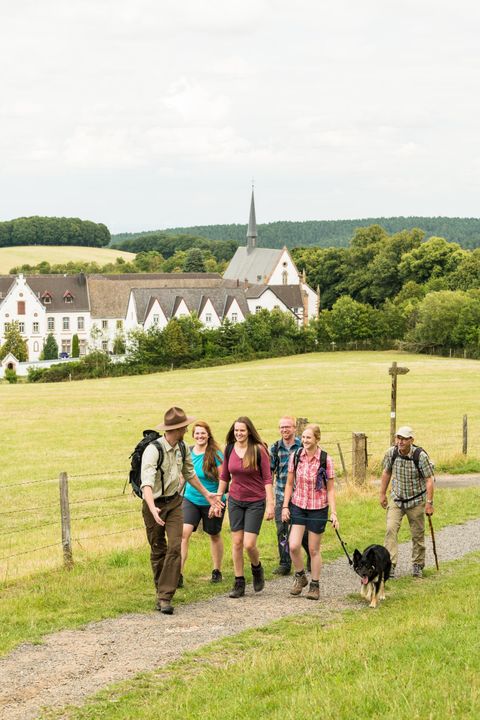 Ein Ranger führt eine Gruppe. Im Hintergrund sieht man das Kloster Mariawald.