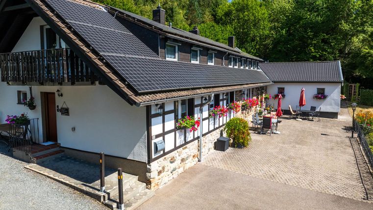 Ein charmantes Haus umgeben von grüner Natur. Die Terrasse ist mit Pflanzen und Möbeln ausgestattet, ideal für entspannte Stunden im Freien.