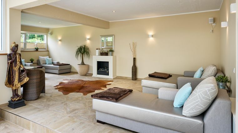 Ein modernes Wohnzimmer mit hellen Wänden und gemütlichen Sofas. Der Raum ist gut beleuchtet und verfügt über dekorative Pflanzen sowie einen Kamin.
