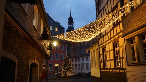 Eine malerische Gasse mit festlicher Beleuchtung und einem Weihnachtsbaum. Die warmen Lichter verleihen der Szenerie eine gemütliche Atmosphäre.