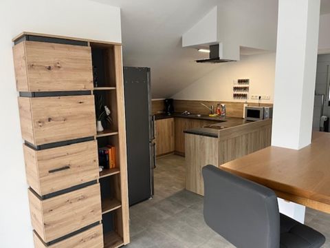 Eine moderne Küche mit Holzregalen und einer großen Arbeitsfläche. Der Raum hat helle Farben und ist gut organisiert.