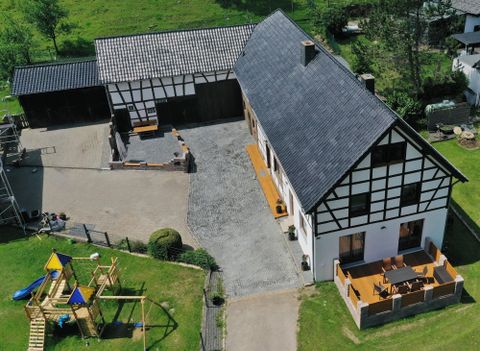 Ein schönes Bauernhaus mit einem großen Garten und einem Spielplatz. Die Terrasse lädt zum Entspannen im Freien ein.