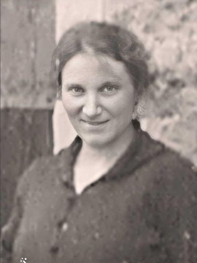 A black-and-white portrait of a woman with a gentle smile. She is wearing a dark sweater and has curly hair.