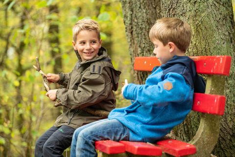Zwei Jungs sitzen lachend auf einer Bank im Nationalpark Eifel.