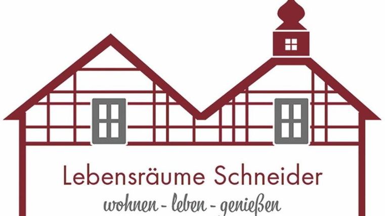 Ein Logo mit zwei stylisierten Häusern im Fachwerkstil. Darunter steht "Lebensräume Schneider" mit dem Slogan "wohnen - leben - genießen".
