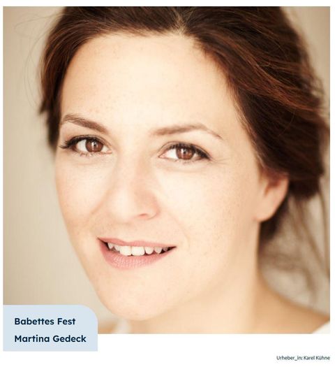 Ein Portrait einer lächelnden Frau mit strahlenden Augen. Der Hintergrund ist neutral, was den Fokus auf ihr Gesicht legt.