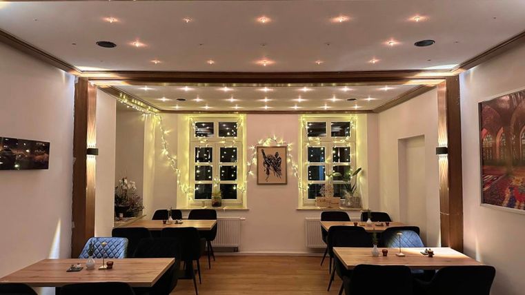 Ein elegantes Restaurant mit modernem Design und stimmungsvollem Licht. Die Tische sind ordentlich gedeckt, und große Fenster bieten Blick nach draußen.