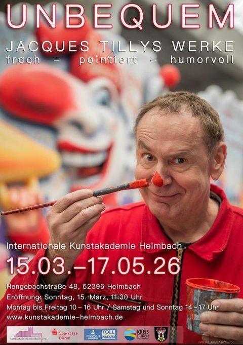 Ein fröhlicher Clown mit einer roten Nase hält einen Pinsel in der Hand. Im Hintergrund sind bunte Clowns und Kunstwerke sichtbar.