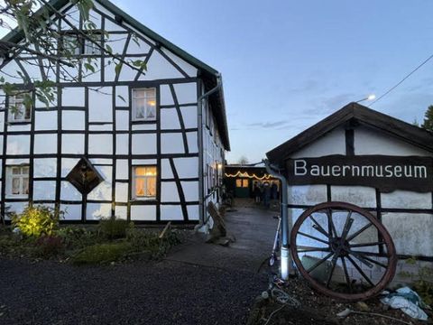 Ein traditionelles Fachwerkhaus mit dem Schild „Bauernmuseum“. Der Eingang wird von einem Wagenrad und grüner Vegetation flankiert.