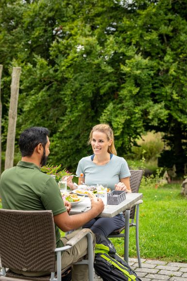 Zwei Personen sitzen an einem gedeckten Tisch voller Essen.