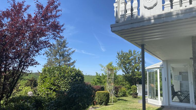 Een modern huis met een mooie tuin. De lucht is helder en blauw, omringd door groene planten.