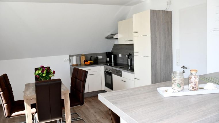 Une cuisine moderne avec une table à manger et des chaises confortables. Des couleurs claires et beaucoup de lumière naturelle créent une atmosphère accueillante.
