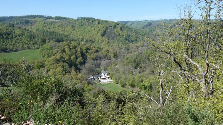 Eine malerische Landschaft mit sanften Hügeln und üppigem Grün. Im Tal ist ein kleines Dorf sichtbar.