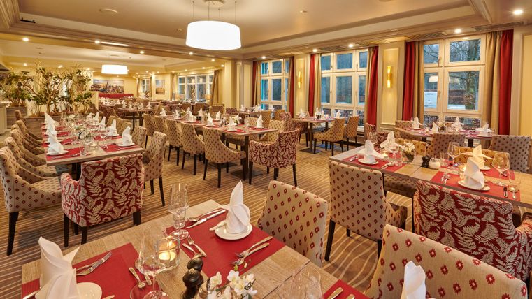 Ein elegantes Restaurant mit gut eingedeckten Tischen und gemütlicher Atmosphäre. Große Fenster lassen viel Tageslicht herein und schaffen eine einladende Stimmung.