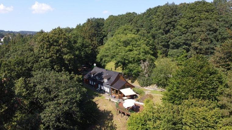 Een charmant huis omringd door weelderig groen en bomen. De heldere lucht en de zonnige sfeer creëren een uitnodigende omgeving.