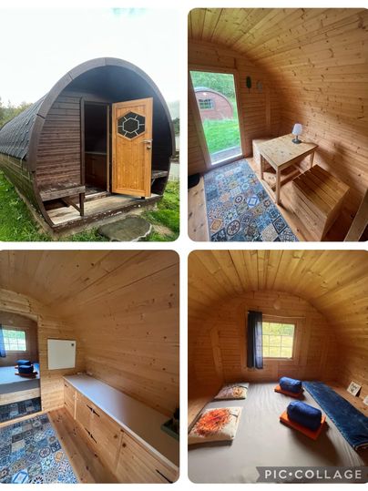 Ein gemütliches Holzhaus in der Natur. Innen ist es schlicht und einladend mit einem Tisch, Matratzen und buntem Bodenbelag.