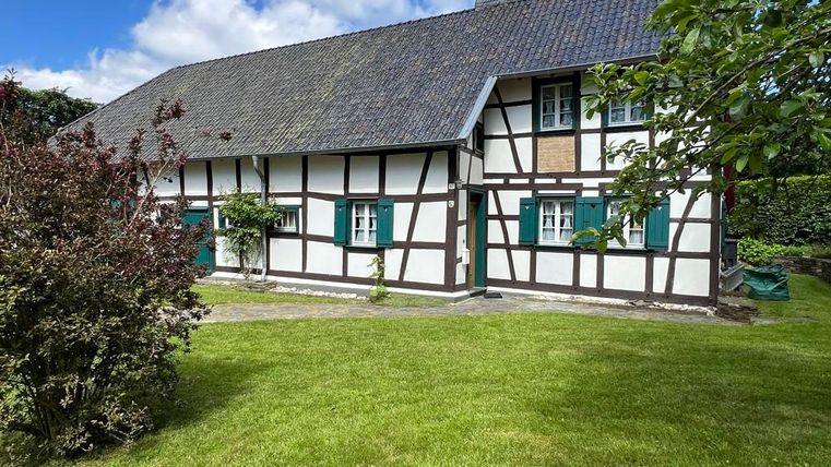Ein traditionelles Fachwerkhaus mit grünem Garten. Der Himmel ist blau und cloudless.