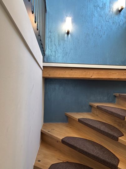 Une moderne escalier en bois avec des marches rembourrées. Les murs sont peints d'un bleu élégant et l'éclairage crée une atmosphère agréable.