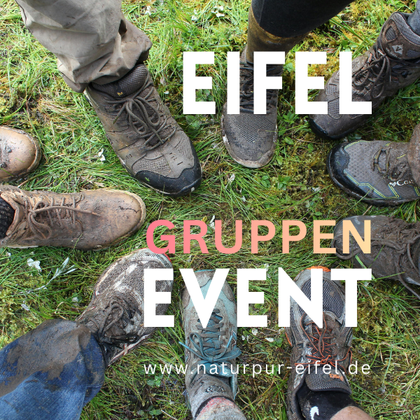 Eine Gruppe von verschiedenen Schuhen steht auf einer grünen Wiese. Die Schuhe sind dreckig, was auf ein Outdoor-Event hindeutet.