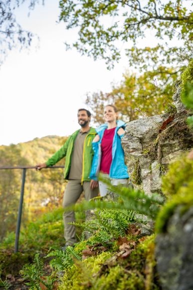 Zwei Wanderer laufen einen Hang im Wald herunter