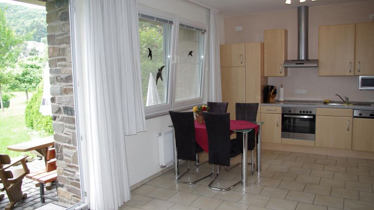 Moderne Küche mit einem Essbereich und Blick auf den Garten. Helle Fenster und ein einladendes Ambiente schaffen eine freundliche Atmosphäre.