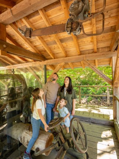 Une famille visite une vieille machine dans un bâtiment historique.
Ils regardent avec curiosité vers le haut à un outil historique suspendu au plafond.