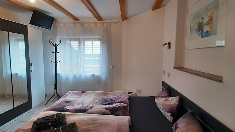 Ein gemütliches Schlafzimmer mit zwei Betten und einer großen Spiegelwand. Das Zimmer hat helle Wände und viel natürliches Licht.