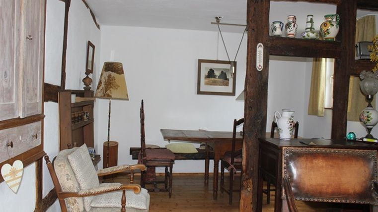 Ein traditionelles Zimmer mit Holzdekor und antiken Möbeln. Im Raum befinden sich ein Tisch, Stühle und dekorative Gegenstände.