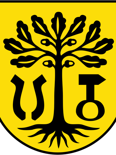 Ein Wappen mit einem schwarzen Baum auf gelbem Hintergrund. Unter dem Baum sind verschiedene Symbole zu sehen, die möglicherweise lokale Bedeutung haben.