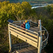 Der oberere Teil des Krawutschketurm auf dem zwei Menschen stehen ist zu sehen. Im Hintergrund ist ein dichter Wald