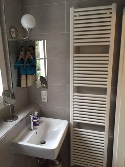 Une salle de bain moderne avec un lavabo et un radiateur à serviettes. Un miroir et une lampe sont également visibles.