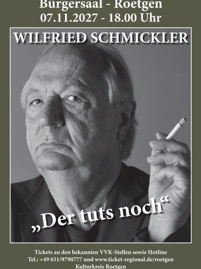 A black-and-white portrait of Wilfried Schmickler. He looks seriously into the camera and holds his hand in a striking manner.