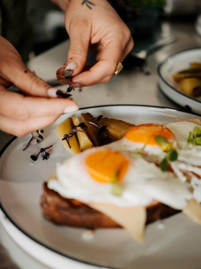 Ein leckeres Frühstücksgericht mit Rühreiern und Brot wird liebevoll angerichtet. Frische Kräuter und Beilagen verleihen dem Teller eine ansprechende Note.