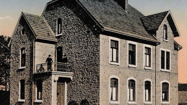 Un presbytère historique en pierre doté d'un balcon. La façade comporte plusieurs fenêtres et un toit en tuiles.