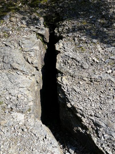 Ein tiefen Riss im Felsen umgeben von steinigen Boden. Das Bild zeigt eine beeindruckende natürliche Spalte in der Landschaft.