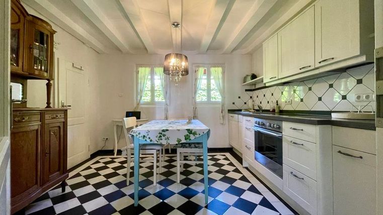 Eine helle Küche mit einem modernen Design und einem Tisch mit Blumenmuster. Der Boden hat ein schickes schwarz-weißes Schachbrettmuster.