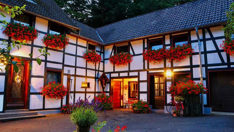 Ein malerisches Fachwerkhaus mit bunten Blumenkästen und einem gemütlichen Innenhof. Die Atmosphäre ist einladend und charmant.